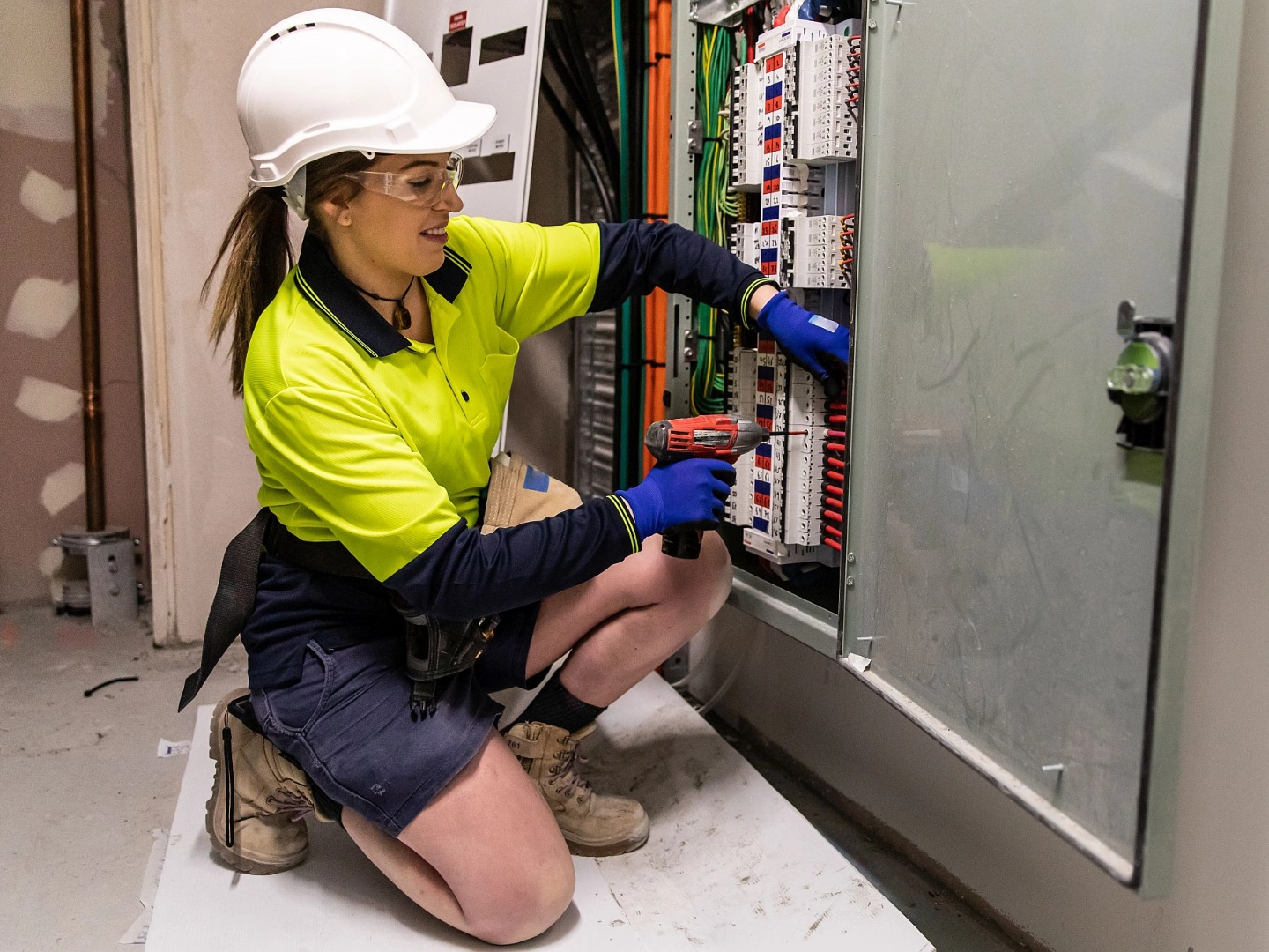 Elektrohandwerkerin arbeitet am Verteilerkasten